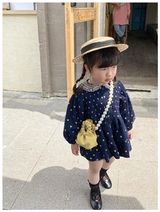 Detail of blue girl's dress with gold hearts, lace collar and yellow pearl chain bag