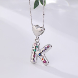 Detailed close-up of letter K pendant with heart clasp and colorful zircon stones