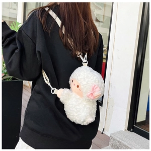 Detail of a soft plush sheep crossbody bag with a pink bow decoration on a model