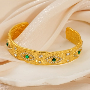 Macro shot of gold textured open bangle featuring malachite evil eye motifs and small crystals