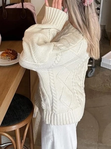 Macro shot of white cable knit sweater texture with ribbed cuffs in a cozy cafe setting