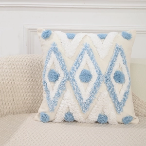 Detailansicht beige Kissenhülle mit blauen geometrischen Rautenmustern und Troddeln