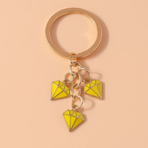 Detail of gold keychain featuring three yellow diamond-shaped enamel charms on a ring