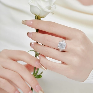 Close-up of a square cut cubic zirconia ring held by a hand with white flowers