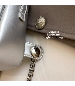 Detail of silver chain bag featuring lion head metal buckle and tight white stitching
