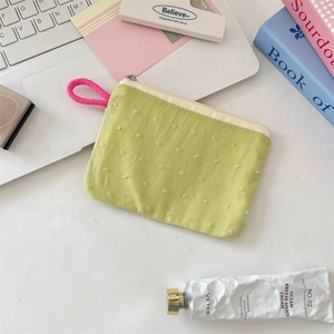 Close-up of green fabric coin purse with 3D polka dot embroidery and woven handle