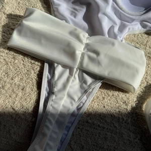 Close-up of white high-cut swimsuit bottom featuring elegant pleated waist details
