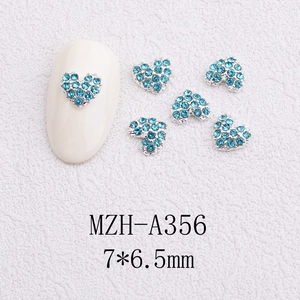 Macro view of blue rhinestone heart nail charms measuring 7x6.5mm on white base