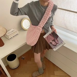 Pink popcorn texture crossbody bag with wide shoulder strap shown in a home interior setting