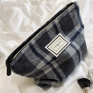 Detail of checkered plaid cosmetic bag featuring premium fabric texture and metal zipper