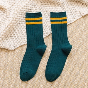Knitted green socks with yellow stripes on beige background for casual autumn style