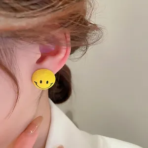 Cute yellow smiley face stud earrings worn by model in a stylish minimalist design