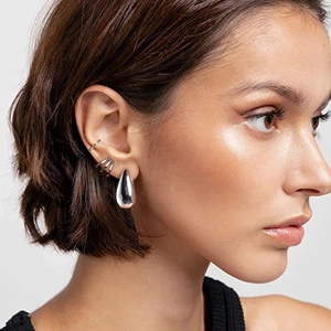 Polished silver teardrop earrings and ear cuffs set shown on a model profile