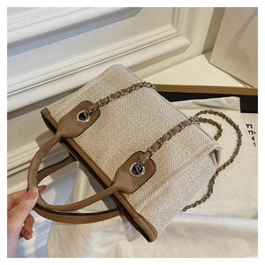 Top view of woven tote bag with brown leather trim and silver chain shoulder strap