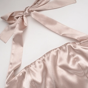 Détail d'une robe dos nu en satin élégante avec nœud au col et texture soyeuse