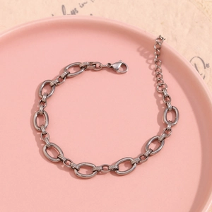 Detail view of silver O-link anklet with lobster clasp and extension chain on pink plate