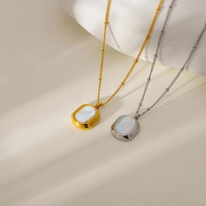 Detailed close-up of oval white shell pendants on gold and silver dainty link chains