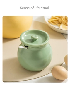 Detail of light green ceramic lard pot with matching lid, white spoon, and matte finish