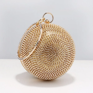 Close-up of a sparkling gold spherical evening bag with rhinestones and metal handle