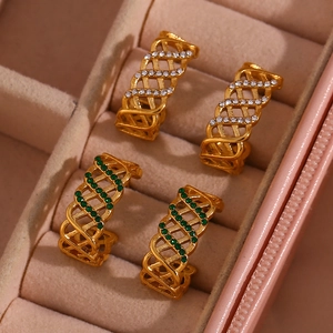 Détail des boucles d'oreilles en C dorées avec zircons verts et blancs en gros plan