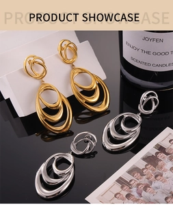 Macro detail of geometric layered oval drop earrings in polished gold and silver finish