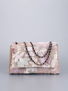 Close-up of floral embroidery and sequins on woven canvas shoulder bag with chain strap