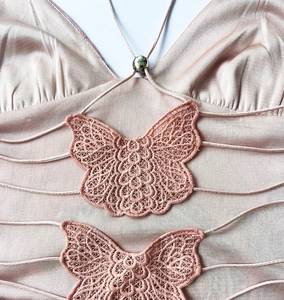 Detail of pink satin dress with mesh butterfly lace appliques and bead strap
