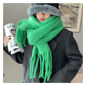 Detail of emerald green chunky knit mohair scarf with thick fringe tassels on a model