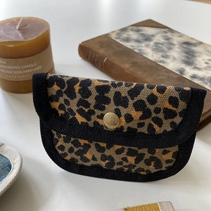 Close-up of a leopard print canvas mini wallet with metal snap button and black piping