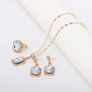 Detail view of gold jewelry set with emerald green crystals on white studio display