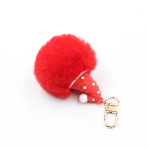 Close-up of red pompom keychain with polka dot Santa hat and gold metal clasp