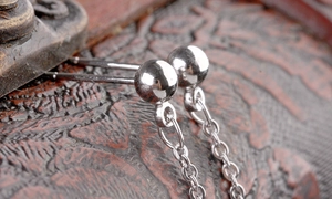 Macro shot of silver pearl tassel long chain earrings on a vintage wood texture