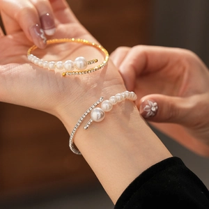 Detail showing elegant gold and silver open cuff bracelets with pearls and rhinestones