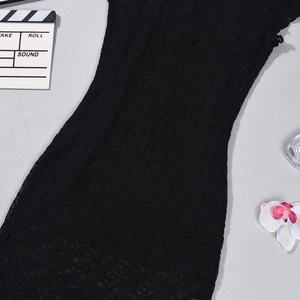 Detailed close-up of intricate black lace texture and floral patterns on a slim-fit dress