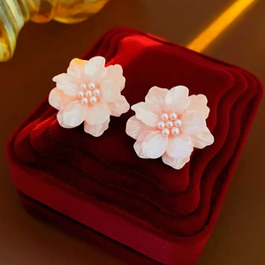 Détail macro de boucles d'oreilles fleurs roses avec pistils de perles blanches