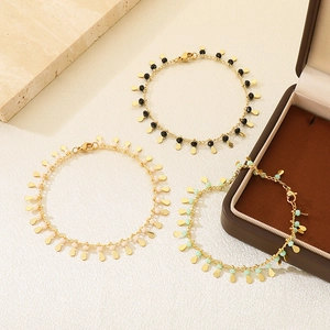 Three elegant beaded gold bracelets with colorful drops and polished metal charms