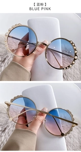 Detail of round sunglasses featuring blue-pink gradient lenses and pearl-encrusted gold frames