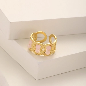 Close-up of golden hammer textured ring with pink stone accents on a display stand