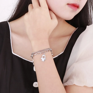 Double-layer silver Hamsa hand charm bracelet with beads on female model wrist