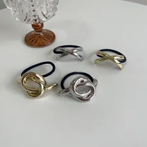 Detail view of minimalist knot and cross design hair rings in gold and silver finish