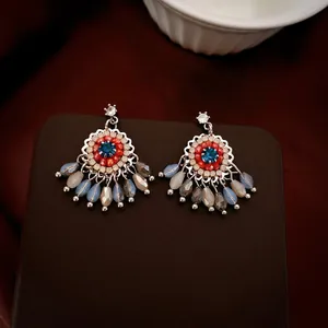 Ethnic flower tassel earrings with crystals and teardrop beads on a leather stand