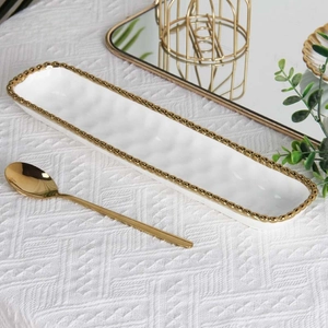 Detail of white ceramic rectangular tray with elegant golden bead rim on white tablecloth
