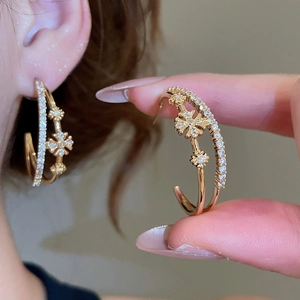 Détail de boucles d'oreilles double couche en C plaquées or 18 carats avec fleurs