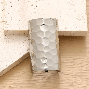 Close-up of a silver minimalist metal hair pin with textured honeycomb pattern on travertine
