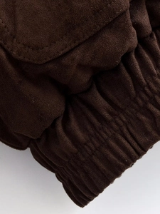 Detail of dark brown faux suede jacket featuring elastic cuff and fine stitching