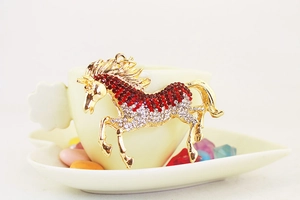 Detailed view of a gold horse keychain featuring red and white sparkling rhinestones