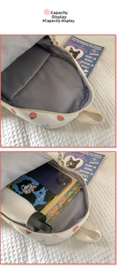 Internal capacity display of a white strawberry canvas backpack with books and a smartphone