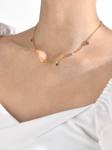 Detail of 18K gold plated necklace with colorful rainbow gems on a model's neck