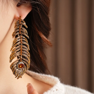 Macro shot of vintage gold feather earrings with amber crystals on female model