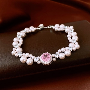 Detailed shot of a French pearl bracelet with pink zircon pendant on leather background